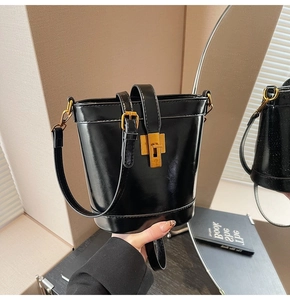 Gros plan d'un sac seau en cuir noir brillant avec un fermoir rectangulaire doré