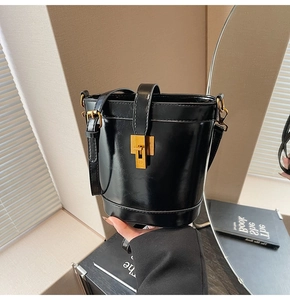 Gros plan détaillé du sac seau en cuir noir brillant avec un fermoir en métal doré chic