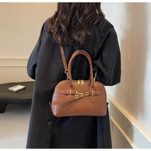 Brown leather handbag shown on model with adjustable strap and gold hardware accents
