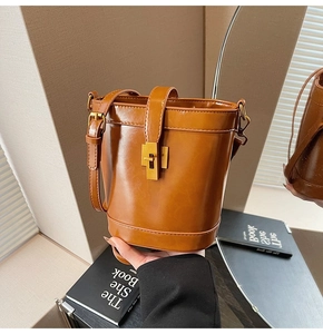 Détail du sac seau en cuir marron avec fermoir doré et bandoulière réglable en gros plan