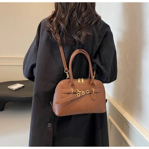 Brown lychee leather bag shown on model back with detachable strap and gold accents