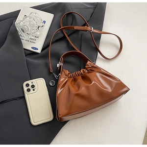 Detail of caramel brown ruched cloud bag with fine PU leather texture on grey suit