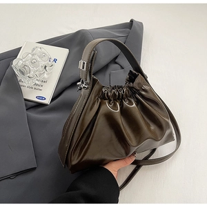 Detail of dark coffee ruched cloud bag with glossy PU leather and wide handle strap