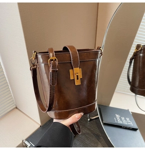 Vue détaillée du sac seau en cuir marron foncé avec fermoir rotatif en métal doré élégant
