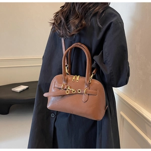 Detail of brown leather handbag featuring gold buckles and adjustable shoulder strap