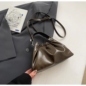 Detailed view of dark brown pleated cloud bag with glossy finish and silver hardware