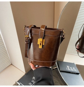 Détail du sac seau marron foncé avec fermoir rotatif doré et texture en similicuir de qualité