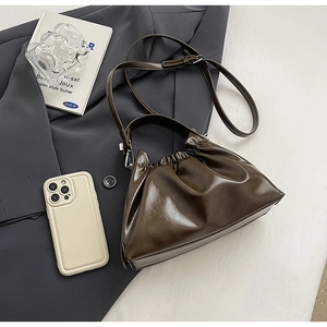 Detail of dark brown ruched cloud bag showing smooth faux leather texture and adjustable strap