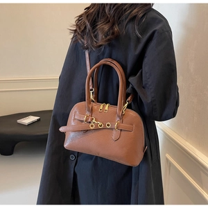 Detailed view of the brown leather bag with golden metallic eyelets and zipper detailing