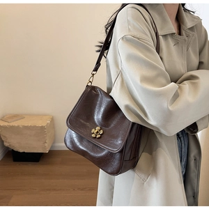 Close-up of vintage dark brown faux leather bag featuring a golden flower-shaped buckle