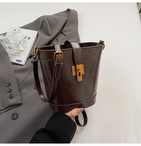 Vue détaillée du sac seau en cuir ciré marron foncé avec boucle tournante dorée de qualité