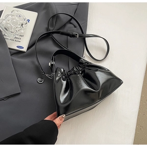 Detail of glossy black cloud bag featuring pleated drawstring closure and shiny finish