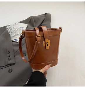 Détail d'un sac seau en cuir ciré marron avec boucle dorée et bandoulière réglable