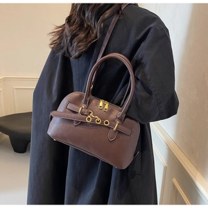 Detail of dark brown retro handbag featuring matte texture and golden ring accents