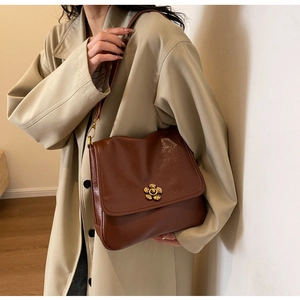 Close-up of a vintage brown leather crossbody bag with a golden flower twist lock