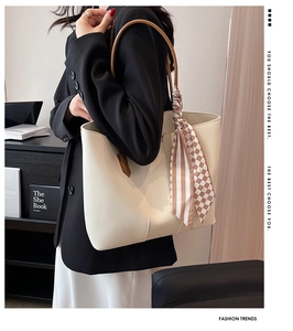 Detail of a minimalist cream tote bag with brown handles and a stylish checkered scarf decor