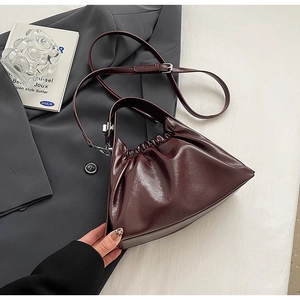 Detail of burgundy ruched cloud bag showing pleated leather texture on a blazer