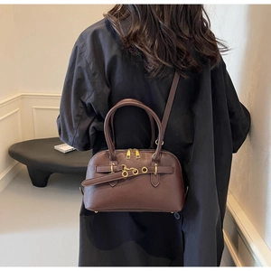 Detail of deep brown Boston bag with golden hardware and textured faux leather finish