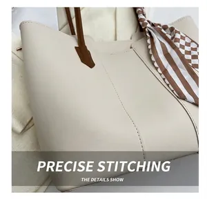 Close-up of precise vertical stitching on a beige tote bag with a brown handle