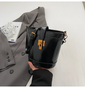 Détail d'un sac seau en cuir ciré noir avec fermoir doré et une poignée de transport
