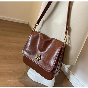Close-up of vintage brown leather bag with golden flower clasp and pleated structure