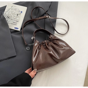 Detail of the dark brown ruched cloud bag showing the glossy finish and shoulder strap