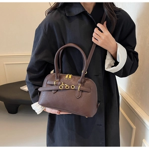 Detailed close-up of dark brown leather shell bag with golden zippers and buckle hardware