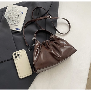 Detailed view of the dark brown ruched cloud bag featuring glossy faux leather and strap