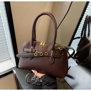 Detail of dark brown leather Boston bag featuring gold ring accents and dual zippers