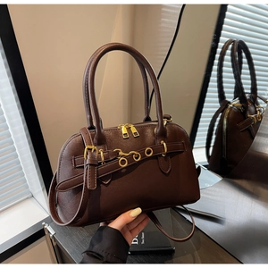 Detailed shot of brown leather Boston bag with gold ring hardware and dual top handles