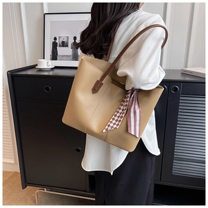 Detail of khaki tote bag with decorative silk scarf and smooth leather texture for work