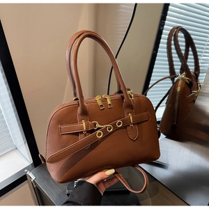 Detail of dark brown leather handbag with gold metal eyelet strap and dual zippers
