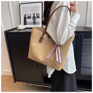 Model wearing a khaki large capacity tote bag with decorative scarf and shoulder strap