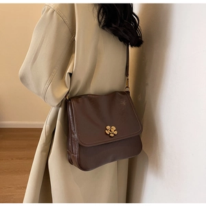 Detail view of a vintage dark brown leather shoulder bag with floral gold metal lock
