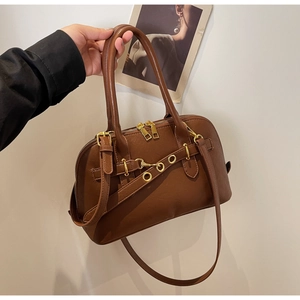 Detail view of brown faux leather handbag with gold hardware and detachable strap