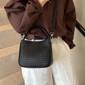 Retro black woven handbag with leather strap shown in a stylish indoor lifestyle setting