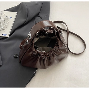 Detail of dark brown glossy dumpling bag with pleated texture and adjustable strap