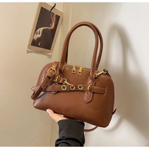 Close-up of brown leather handbag with gold hardware and stylish metal eyelet belt detail