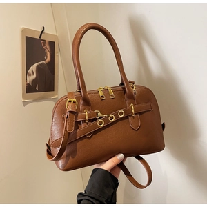 Close-up of retro brown Boston bag showing premium leather texture and gold metal ring details