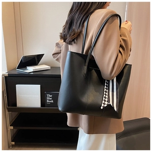 Detail of black large tote bag with silk scarf on shoulder of woman in brown blazer