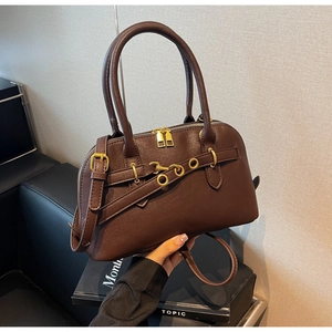 Close-up of dark brown lychee pattern leather handbag with gold metal buckles and strap