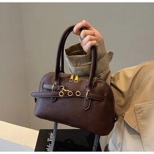 Detail of dark brown matte leather handbag with gold eyelet buckle and lobster clasp