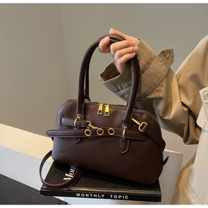 Close-up of brown litchi pattern leather handbag with golden metal eyelet and strap