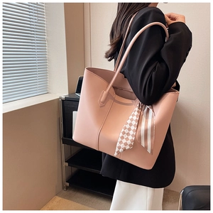 Detail of pink leather tote bag with decorative silk scarf and slim shoulder straps