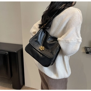 Detail of a vintage black leather shoulder bag with a stylish golden flower clasp lock