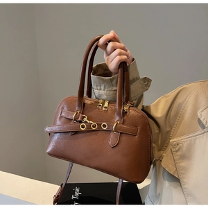 Detail of brown Boston handbag with golden metal rings and adjustable crossbody strap