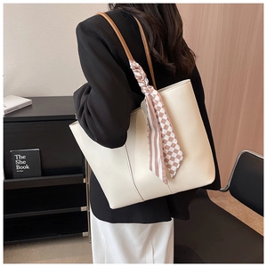 Detail of a beige tote bag with a patterned silk scarf on handle for commute style