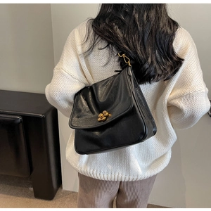 Detail of vintage black leather crossbody bag with a golden floral metal buckle