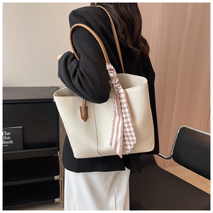 Detail of a creamy white tote bag with brown straps and a stylish decorative scarf