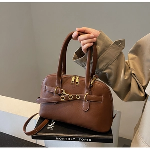 Detailed view of caramel brown handbag with gold dual zippers and decorative metal eyelets
